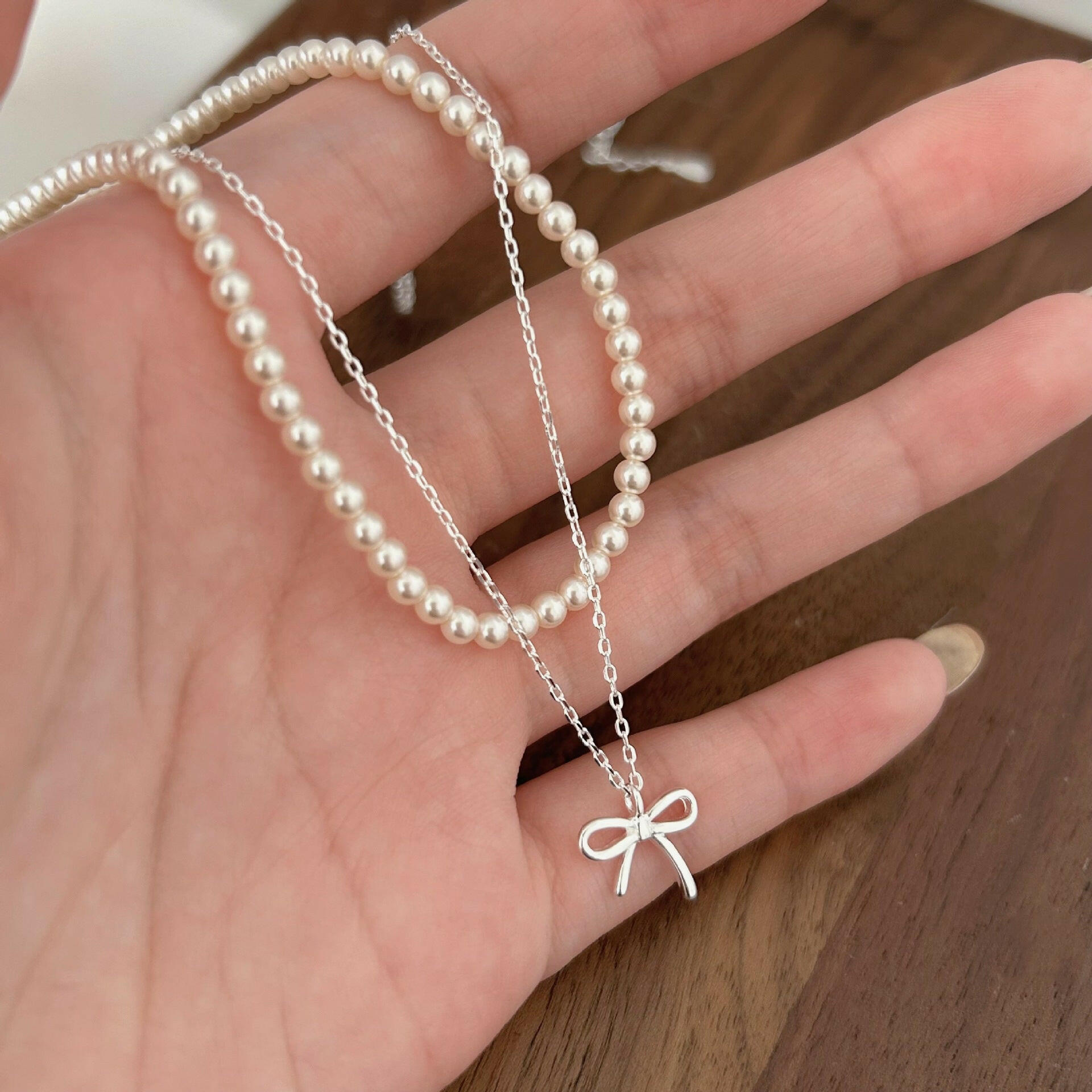 holding s925 sterling silver light luxury pearl bow dual layer stack wearing necklace female korean summer versatile clavicle chain